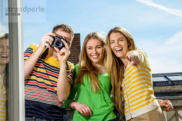 Drei junge Freunde mit Kamera auf dem Dach