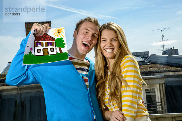 Junges Paar mit Hauszeichnung auf dem Dach