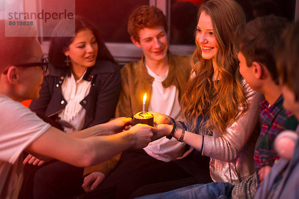 Gruppe von Teenagern  die um den Geburtstagskuchen sitzen