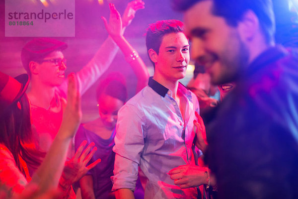 Teenager-Junge  umgeben von einer Gruppe von Leuten  die auf einer Party tanzen.