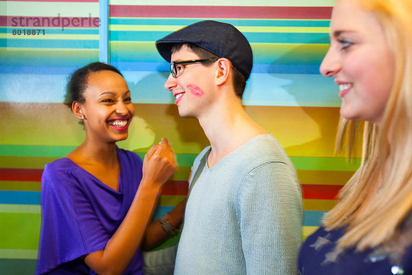 Junger Mann mit Lippenstiftfleck auf der Wange  Frauen lachend