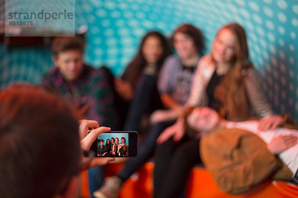 Teenager-Junge fotografiert Gruppe von Freunden mit dem Smartphone