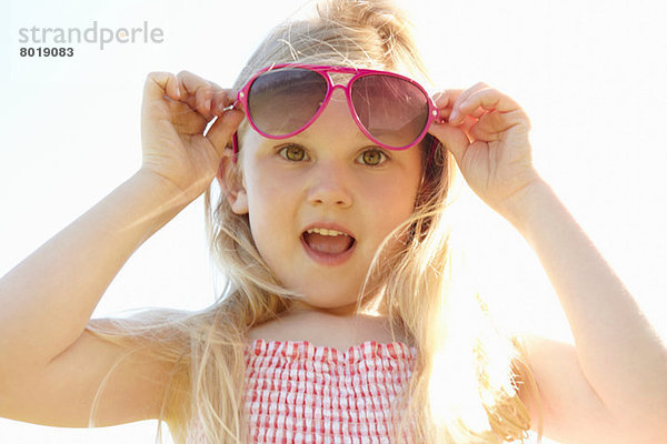 Kind setzt an heißen  sonnigen Tagen eine Sonnenbrille auf.