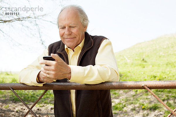 Älterer Mann lächelt Nachricht auf dem Handy an