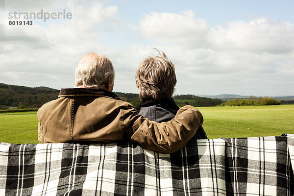 Rückansicht des Seniorenpaares  das die Landschaft auf dem Feld genießt.