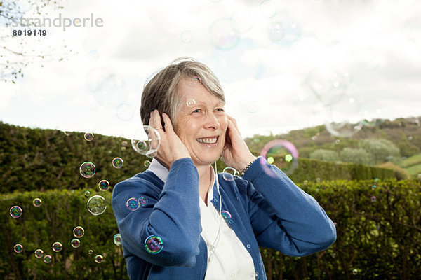 Seniorenfrau mit Ohren und Lachen über Blasen