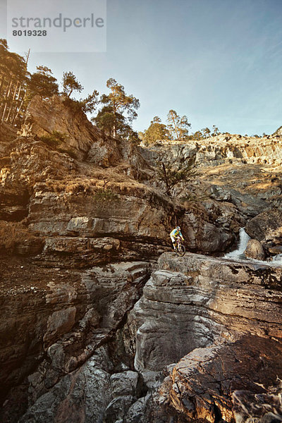 Mann Mountainbiken auf Felsen bei Klippen