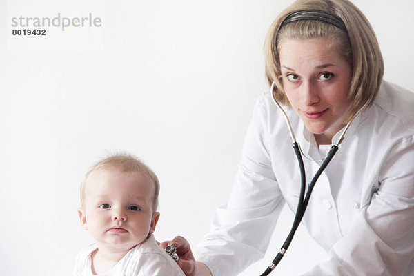 Ärztin untersucht die Atmung des Babys