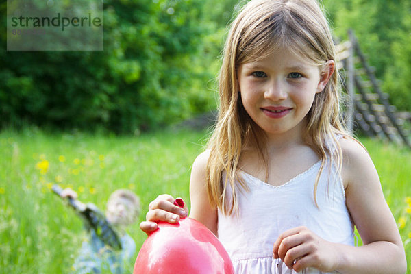 Nahes Porträt eines jungen Mädchens mit rotem Ballon