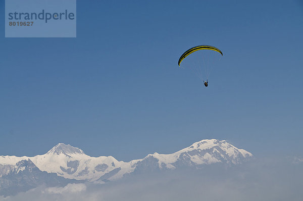 Gleitschirmsegler in der Luft  Annapurna-Kette hinten