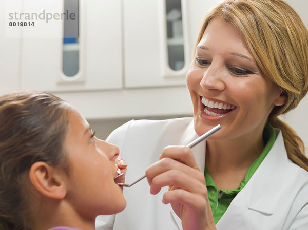 Zahnarzt schaut auf die Zähne eines jungen Mädchens