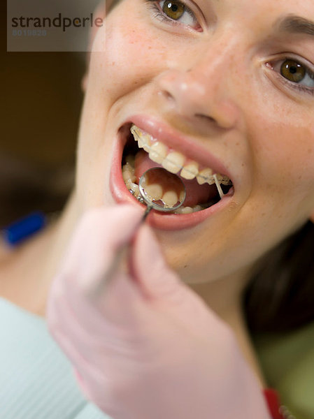Zahnarzt untersucht die Zähne der jungen Frau  Nahaufnahme
