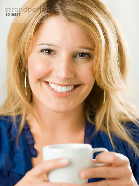 Mittlere erwachsene Frau hält Tasse und lächelt  Portrait