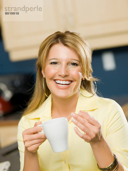 Mittlere erwachsene Frau hält Tasse und lächelt  Portrait