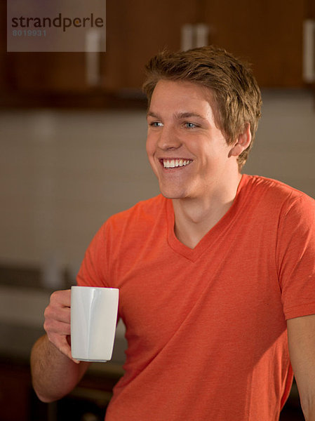 Junger Mann mit einer Tasse Kaffee in der Küche