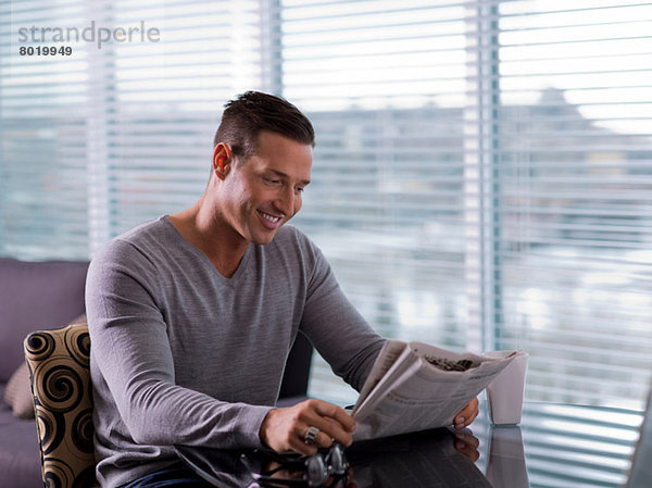 Mittlerer Erwachsener Mann sitzt und liest Zeitung
