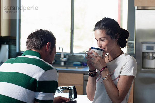 Junges Paar genießt Kaffee in der Küche  lächelnd