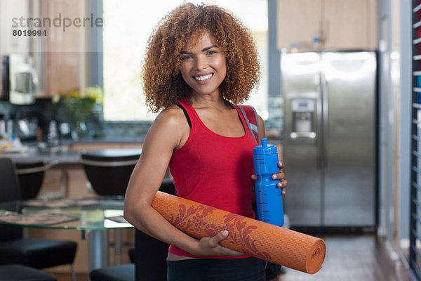 Mittlere erwachsene Frau mit Yogamatte und Wasserflasche  Portrait