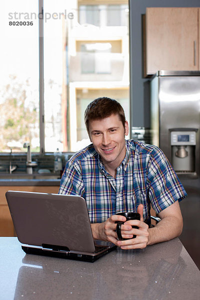 Mittlerer Erwachsener Mann mit Laptop in der Küche  Porträt