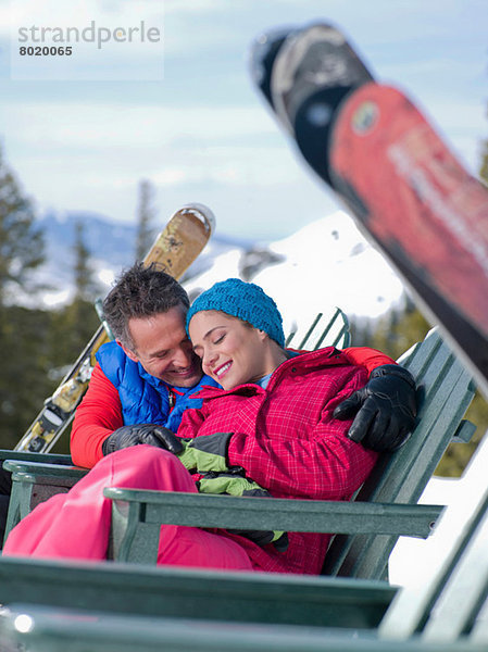 Erwachsener Mann und junge Frau entspannen gemeinsam im Skigebiet