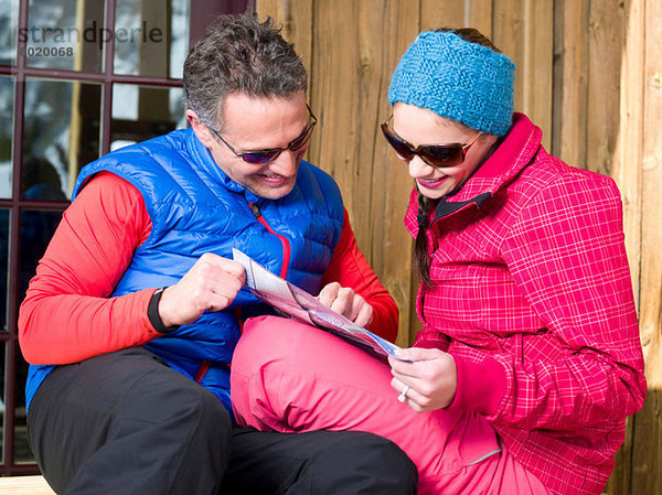 Erwachsener Mann und junge Frau auf der Karte im Skigebiet