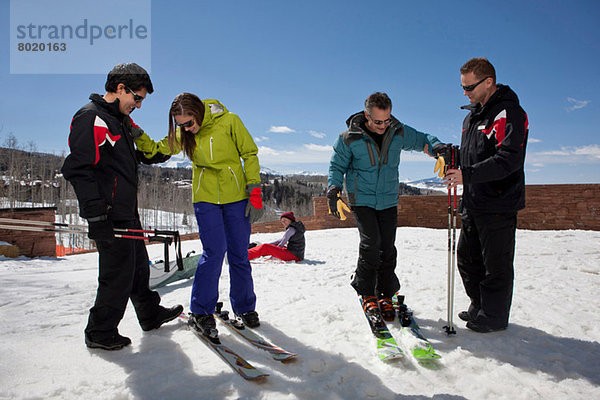 Erwachsener Mann und junge Frau mit Skilehrern auf der Piste