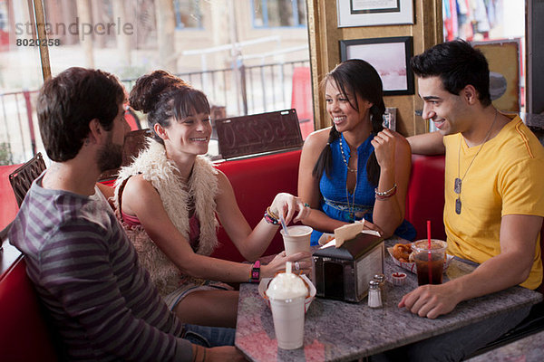 Vier Freunde sitzen zusammen im Diner  lächelnd