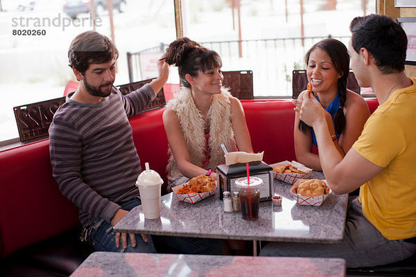 Vier Freunde sitzen zusammen im Diner  lächelnd