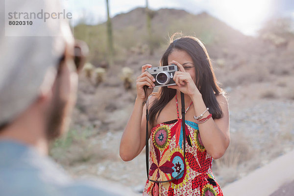 Junge Frau fotografiert Freund auf der Wüstenstraße