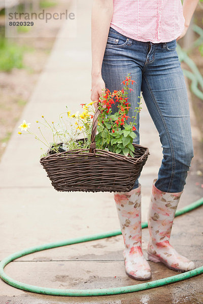 Mittlere erwachsene Frau mit Blumenkorb im Gartencenter  niedriger Schnitt