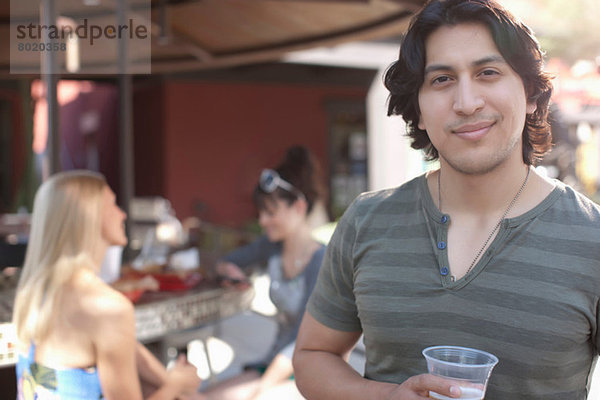 Junger Mann mit Getränk und Lächeln im Außencafé  Portrait