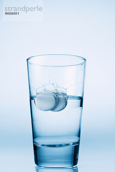 In ein Glas Wasser fallende Tabletten