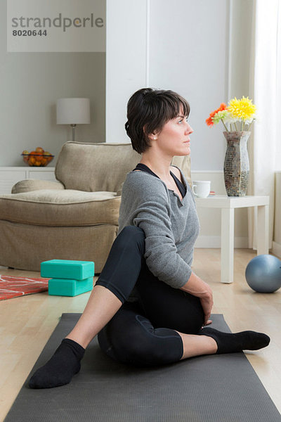 Mittlere erwachsene Frau beim Yoga zu Hause