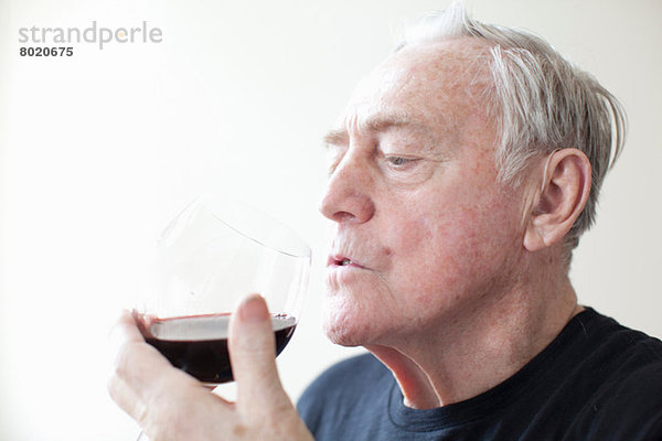 Senior Mann trinkt Rotwein