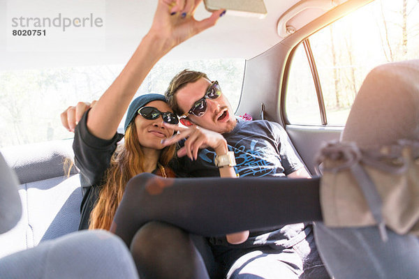 Paar auf dem Rücksitz im Auto fotografiert sich selbst