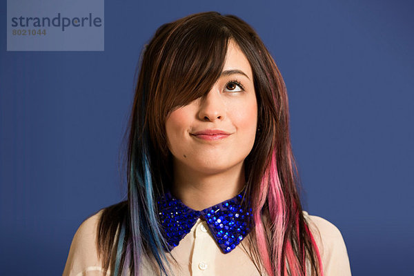 Porträt einer jungen Frau mit gefärbtem Haar und blauem Paillettenhalsband