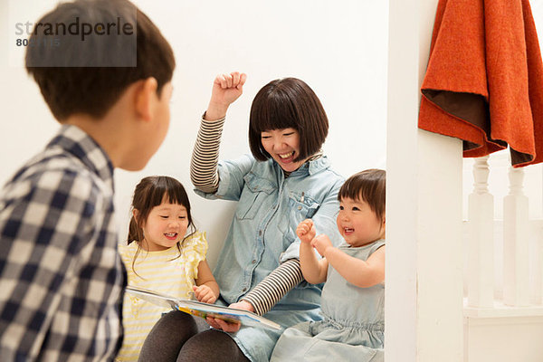 Mutter und Kinder lachen über das Märchenbuch