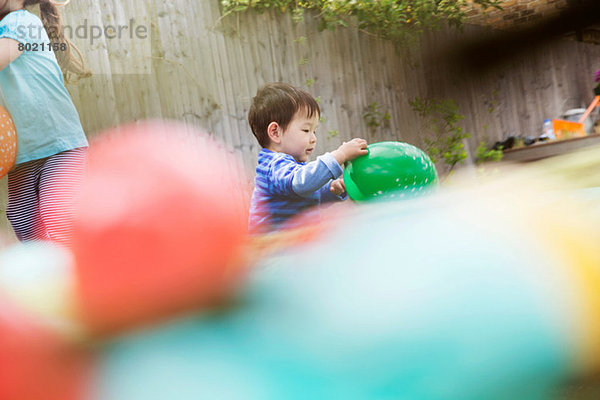 Männliches Kleinkind beim Spielen im Garten mit Ballon