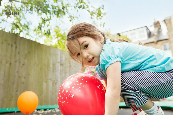 Junges Mädchen spielt im Garten mit Luftballons