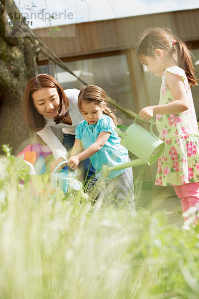 Mutter und Töchter gießen Garten