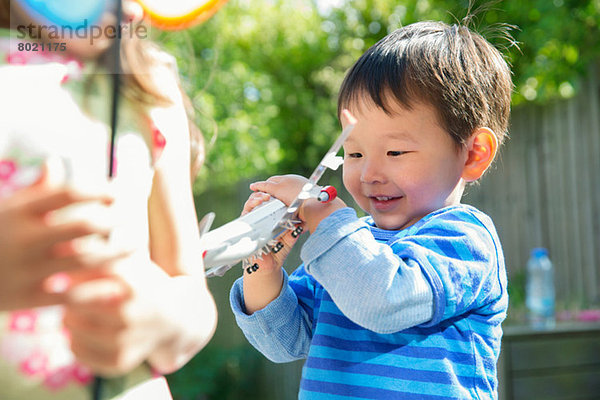 Männliches Kleinkind im Garten mit Spielzeugflugzeug