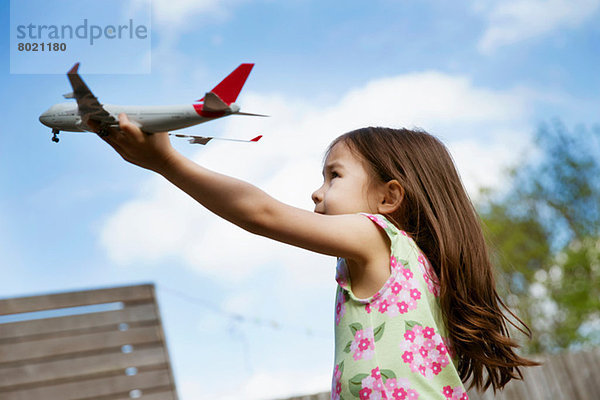 Junges Mädchen im Garten spielt mit Spielzeugflugzeug