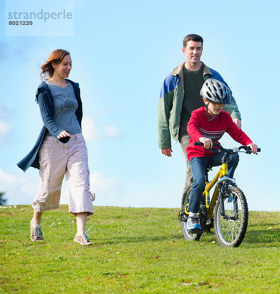 Eltern beobachten den Sohn beim Fahrradfahren