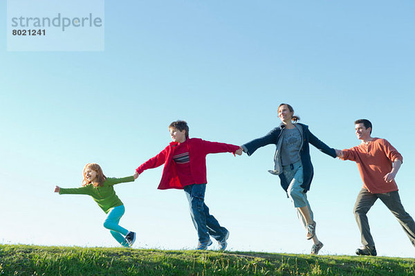 Eltern und zwei Kinder beim Laufen und Händchenhalten