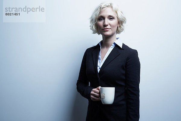 Studio-Porträt einer blonden Geschäftsfrau mit einer Tasse Tee