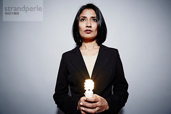 Studio-Porträt einer Geschäftsfrau mit Energiesparlampe