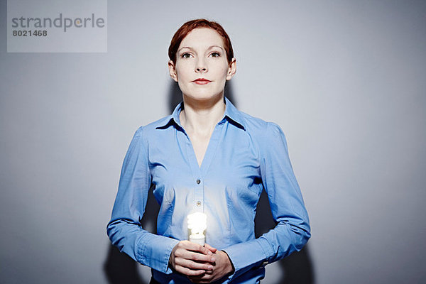 Studio-Porträt einer jungen Geschäftsfrau mit Glühbirne