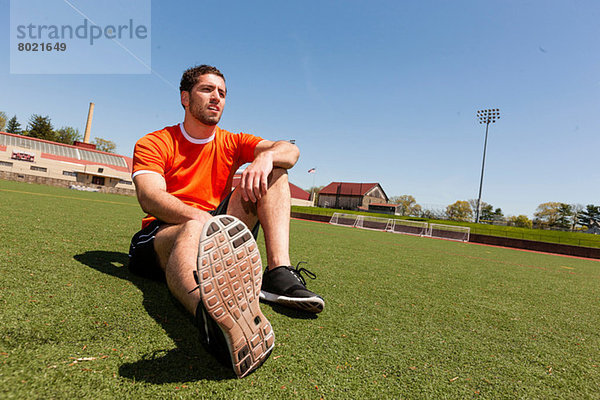 Junger Mann macht Pause auf Sportstadionrasen