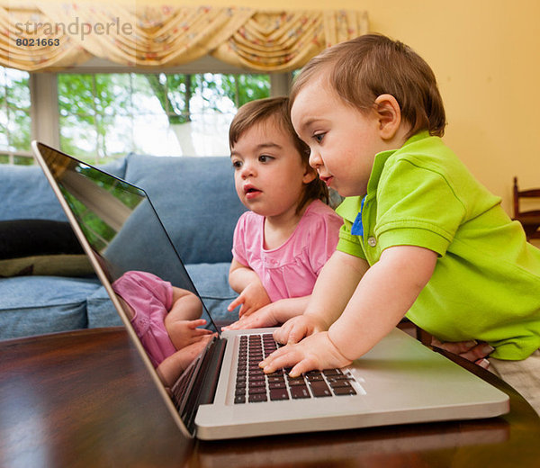 Zwei junge Kleinkinder beim Spielen mit dem Laptop