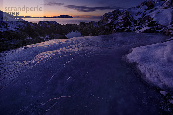 Fjord mit Eis und Felsen bei untergehender Sonne